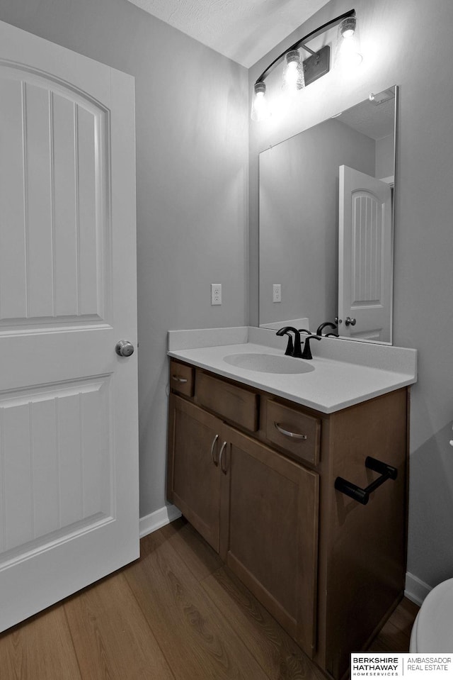 bathroom featuring toilet, vanity, and wood-type flooring