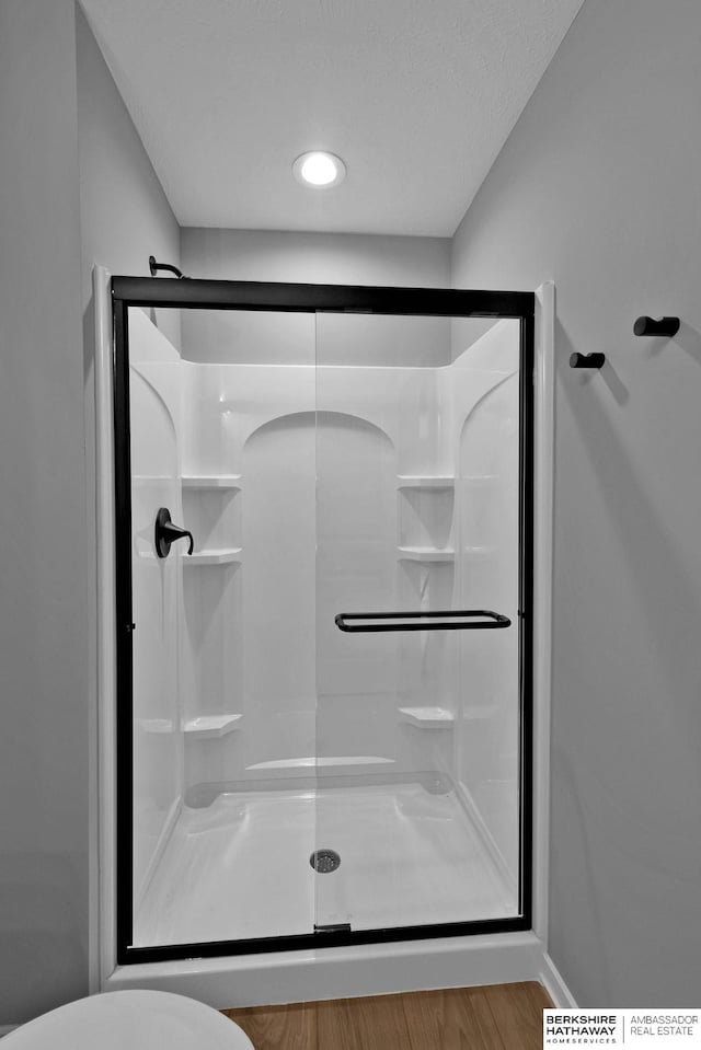 bathroom featuring wood-type flooring, toilet, and walk in shower