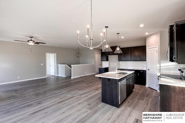 kitchen with a center island with sink, decorative backsplash, sink, hanging light fixtures, and ceiling fan with notable chandelier