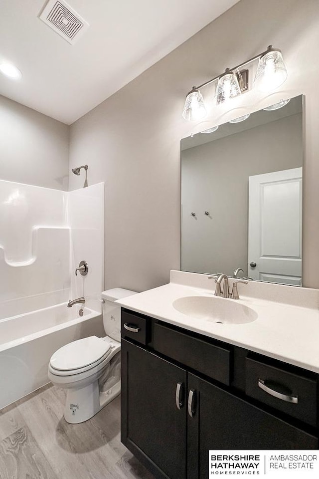 full bathroom featuring hardwood / wood-style floors, shower / bathing tub combination, vanity, and toilet