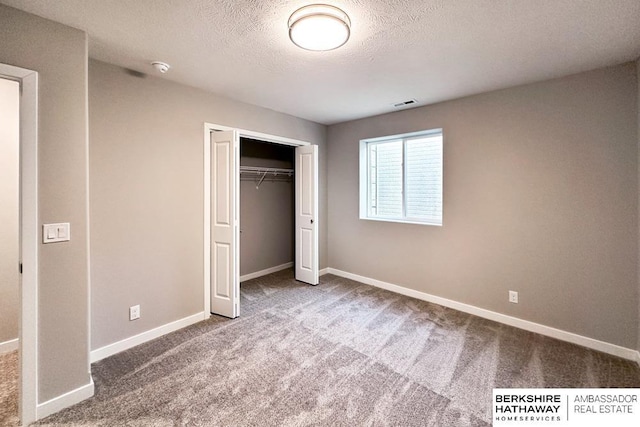 unfurnished bedroom featuring a textured ceiling, a closet, and carpet flooring