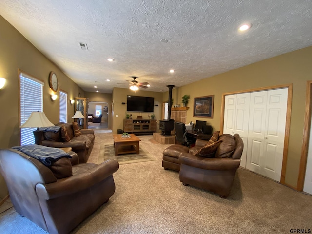 living room featuring visible vents, a healthy amount of sunlight, carpet, recessed lighting, and a wood stove