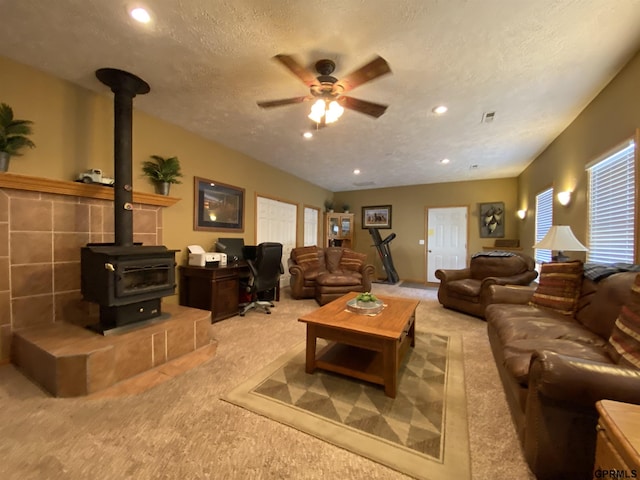 living room featuring ceiling fan, carpet flooring, recessed lighting, a wood stove, and a textured ceiling