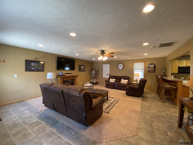 living area featuring recessed lighting, visible vents, a textured ceiling, and a fireplace