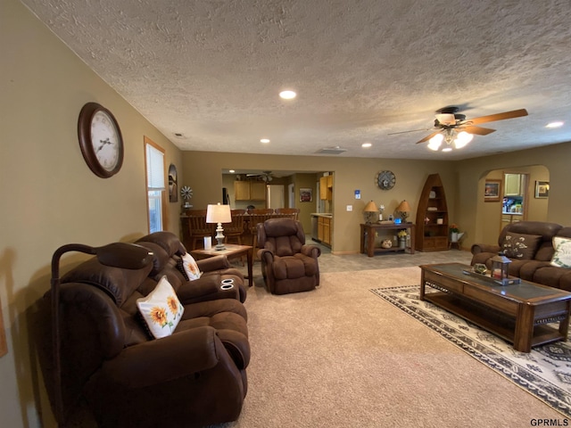 living area with light carpet, a textured ceiling, recessed lighting, arched walkways, and ceiling fan