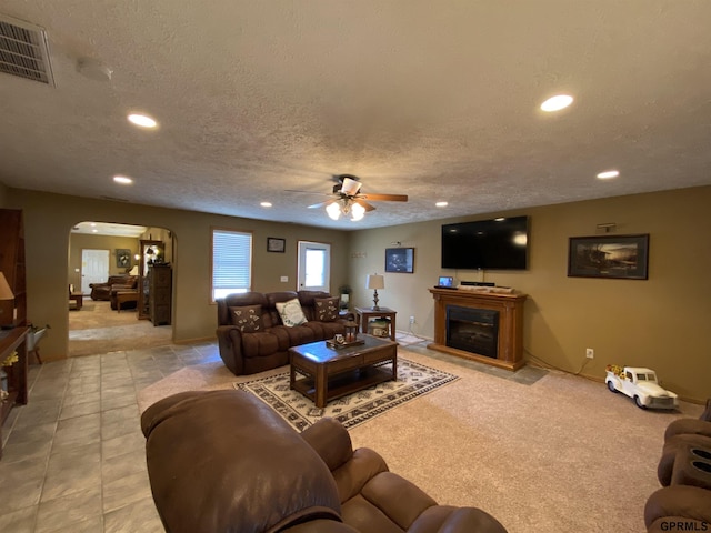 living room featuring visible vents, a fireplace, recessed lighting, arched walkways, and a textured ceiling