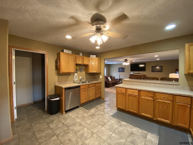 kitchen featuring dishwasher, light countertops, open floor plan, and a sink