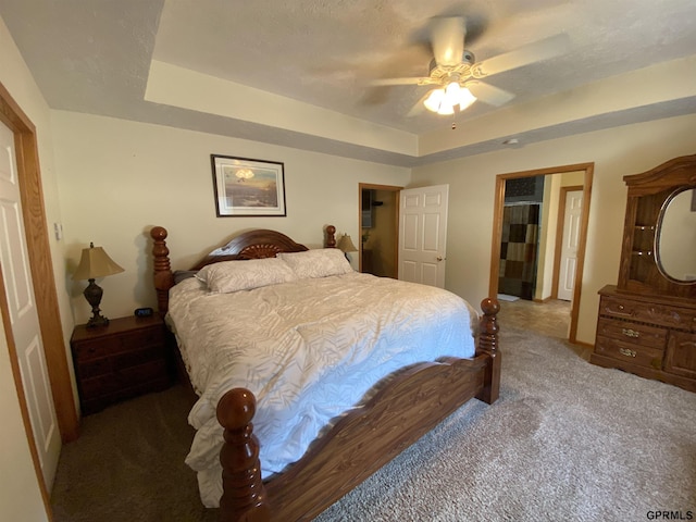 carpeted bedroom featuring a raised ceiling, a ceiling fan, and a textured ceiling