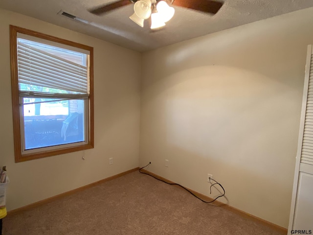 empty room with visible vents, baseboards, ceiling fan, light carpet, and a textured ceiling