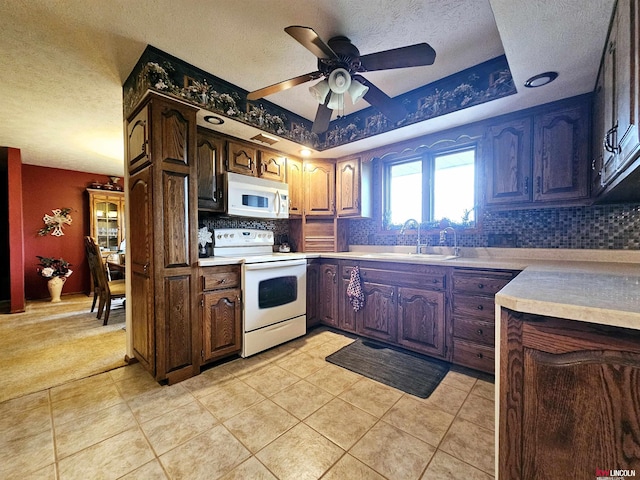 kitchen featuring sink, a textured ceiling, backsplash, and white appliances