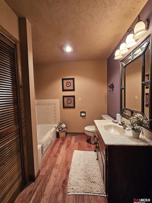 bathroom with vanity, a bathing tub, hardwood / wood-style floors, and a textured ceiling