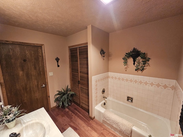 bathroom with vanity, hardwood / wood-style floors, a textured ceiling, and a tub to relax in