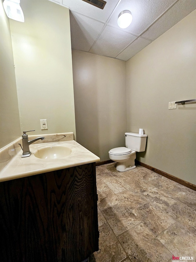 bathroom with vanity, a drop ceiling, and toilet