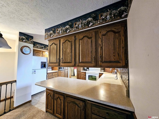 kitchen featuring light tile patterned flooring, sink, white appliances, kitchen peninsula, and a textured ceiling