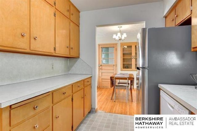 kitchen featuring light wood-type flooring, pendant lighting, stainless steel refrigerator, and decorative backsplash