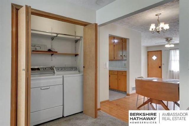 washroom with a chandelier, independent washer and dryer, a textured ceiling, and light wood-type flooring