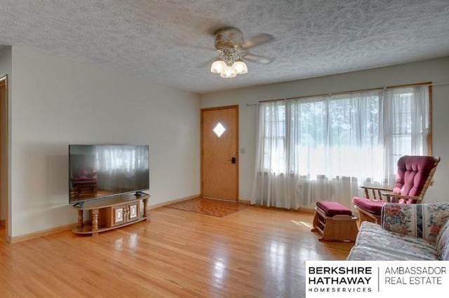 living room featuring ceiling fan, hardwood / wood-style floors, and a textured ceiling