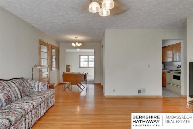 living room with a chandelier, light hardwood / wood-style flooring, and a textured ceiling