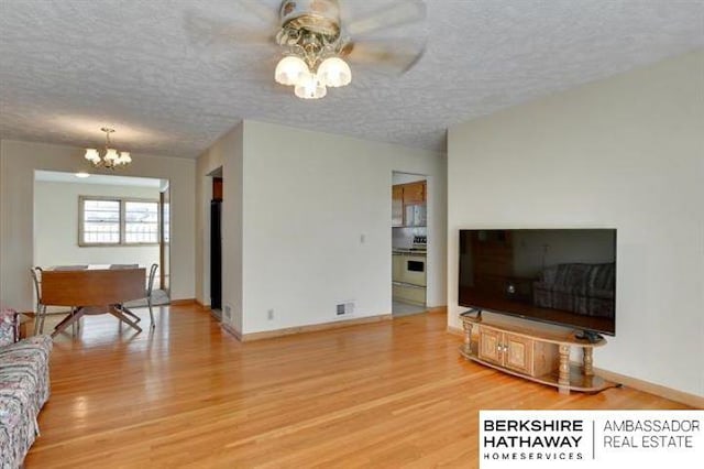 living room with an inviting chandelier, wood-type flooring, and a textured ceiling