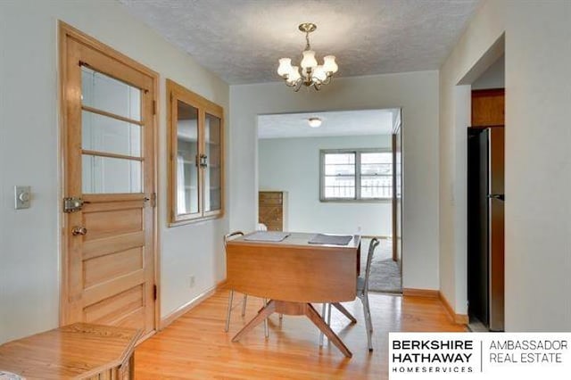 dining space featuring a notable chandelier, light hardwood / wood-style floors, and a textured ceiling