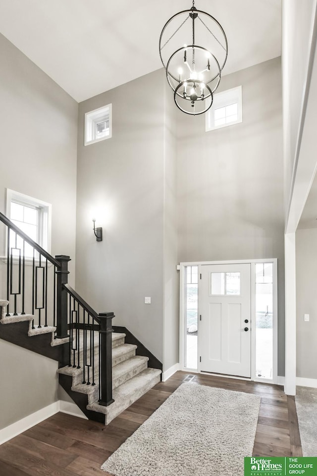 foyer entrance with a high ceiling, dark hardwood / wood-style flooring, and a chandelier