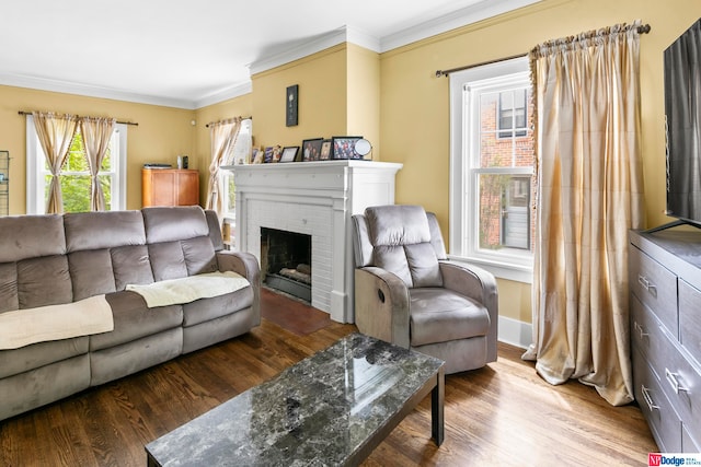 living room featuring ornamental molding, wood-type flooring, and a brick fireplace