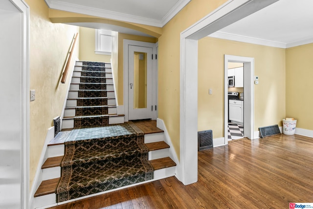 stairs with wood-type flooring and crown molding