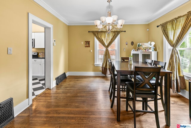 dining room featuring hardwood / wood-style flooring, crown molding, and an inviting chandelier