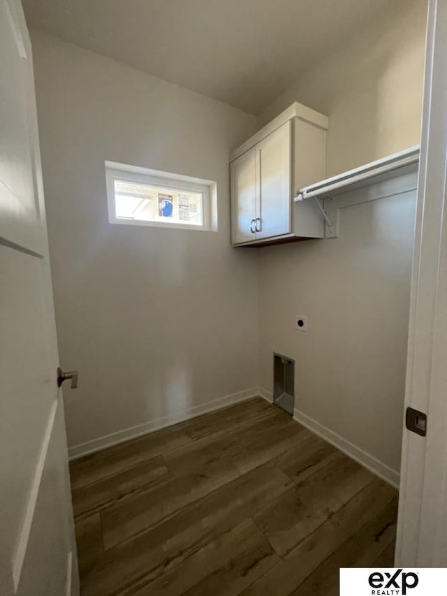 clothes washing area with cabinet space, electric dryer hookup, baseboards, and wood finished floors