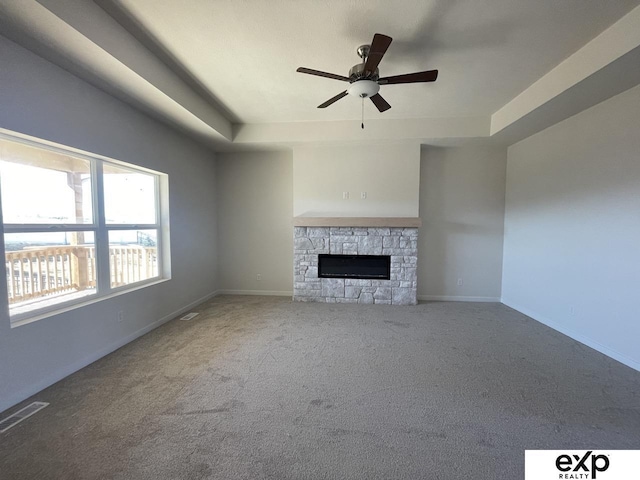 unfurnished living room with visible vents, baseboards, a raised ceiling, carpet flooring, and a fireplace