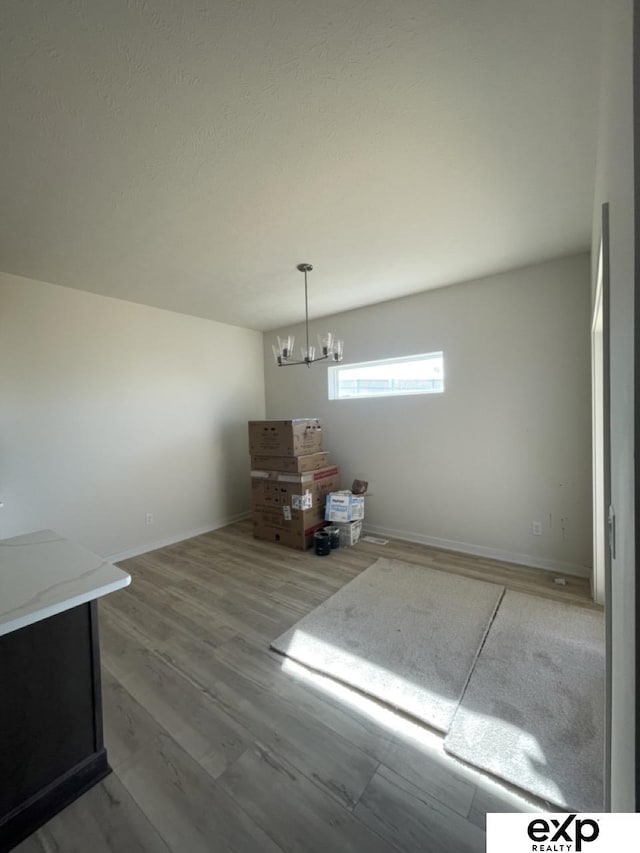 unfurnished dining area with baseboards, a chandelier, and wood finished floors