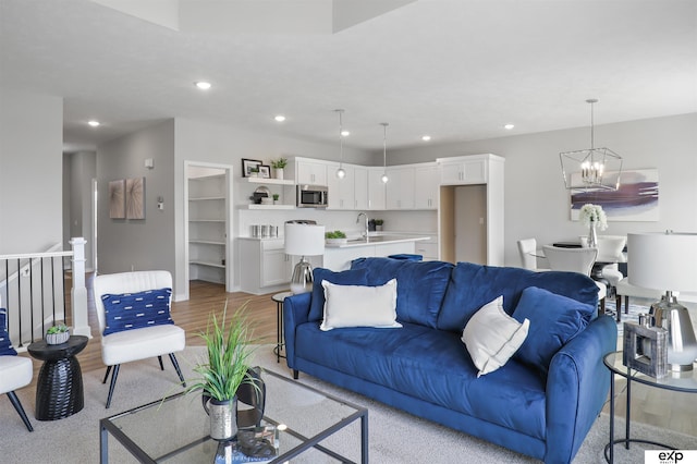 living room with sink, an inviting chandelier, and light wood-type flooring