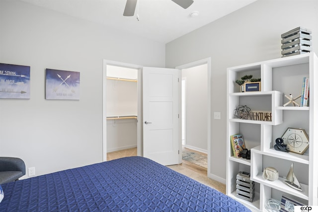 bedroom featuring a walk in closet, a closet, light colored carpet, and ceiling fan