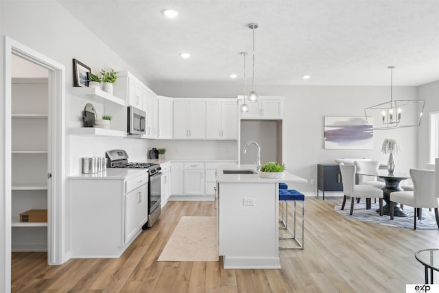 kitchen featuring appliances with stainless steel finishes, light hardwood / wood-style flooring, a center island with sink, sink, and white cabinetry