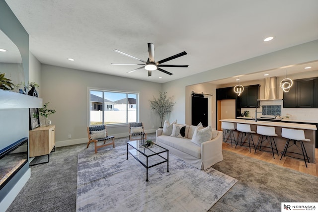 living room featuring wood-type flooring, sink, and ceiling fan