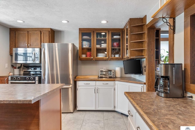 kitchen featuring white cabinetry, a textured ceiling, stainless steel appliances, and light tile patterned floors