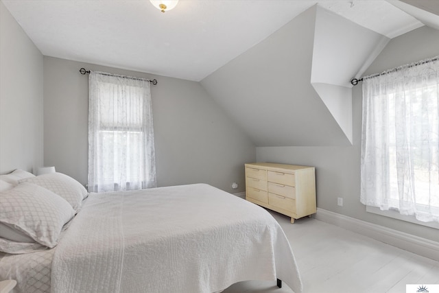 bedroom with light wood-type flooring and vaulted ceiling