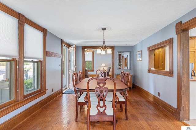 dining room with a healthy amount of sunlight, an inviting chandelier, and hardwood / wood-style floors