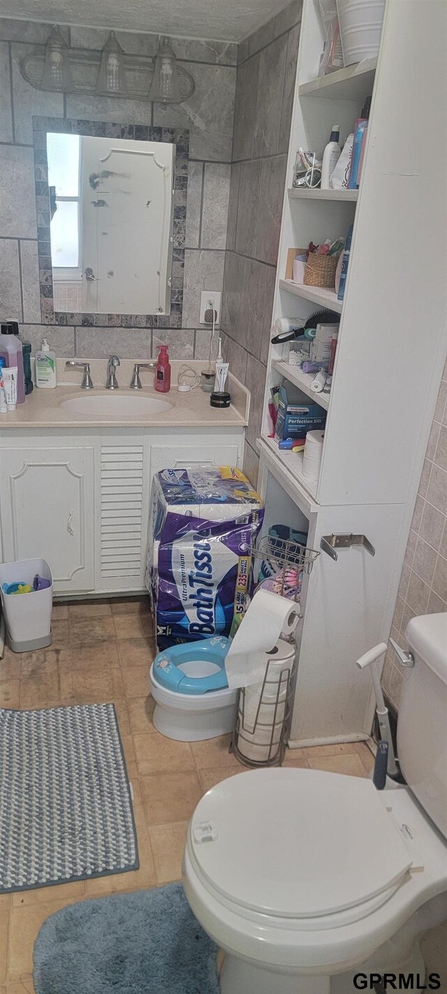 bathroom featuring tile patterned floors, tile walls, decorative backsplash, sink, and toilet