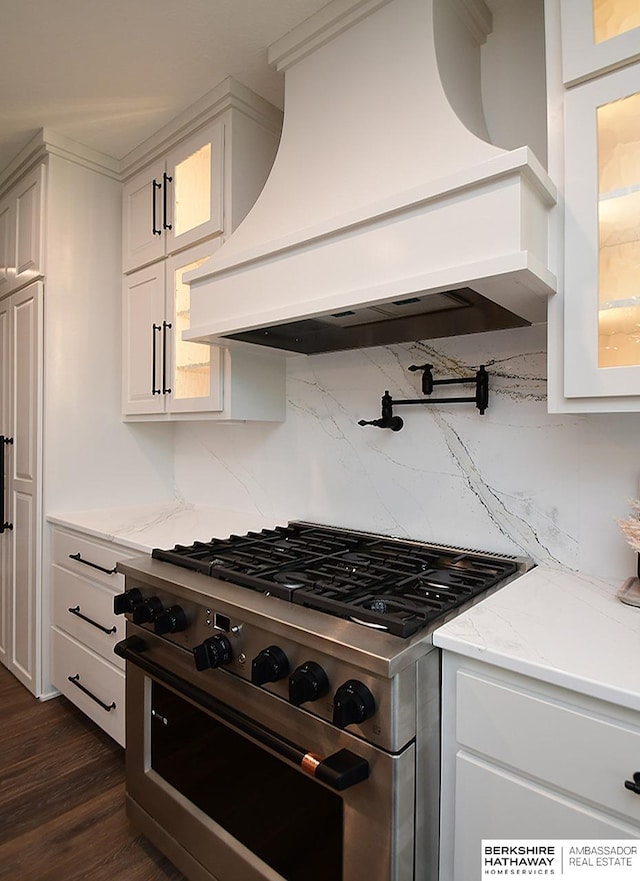 kitchen with dark hardwood / wood-style flooring, backsplash, light stone counters, custom exhaust hood, and high end stainless steel range oven