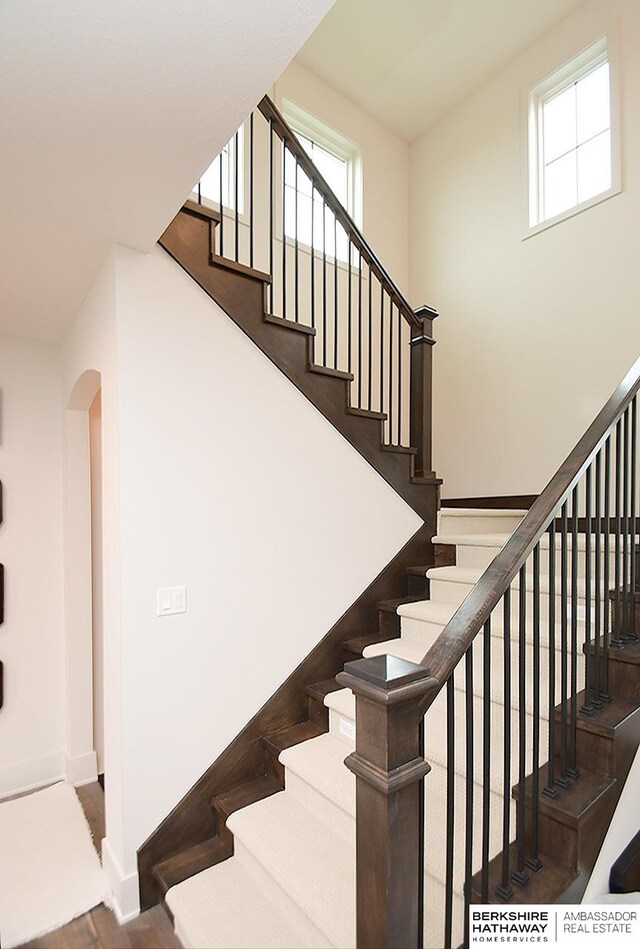 stairs featuring hardwood / wood-style flooring and a high ceiling