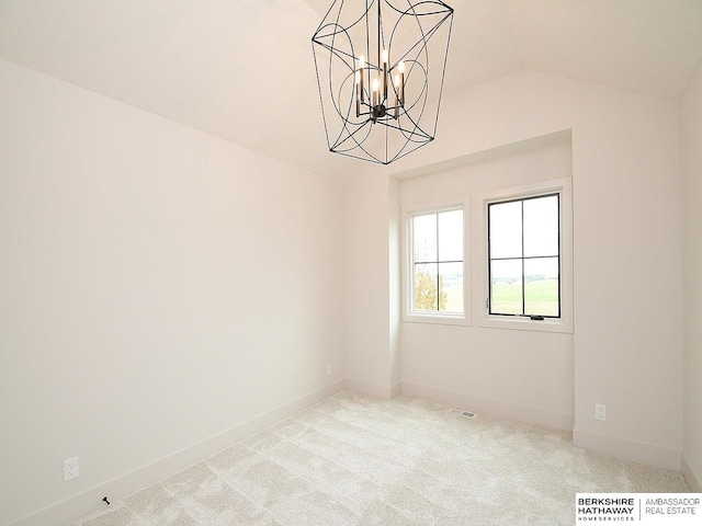 carpeted spare room featuring vaulted ceiling and a chandelier