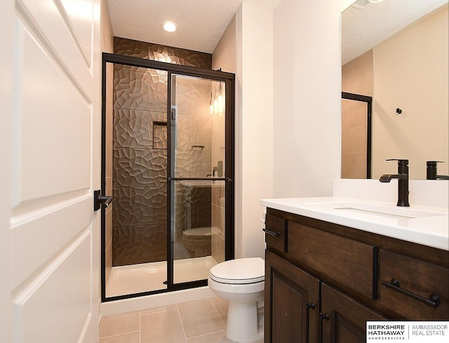 bathroom with a textured ceiling, toilet, tile patterned floors, vanity, and walk in shower