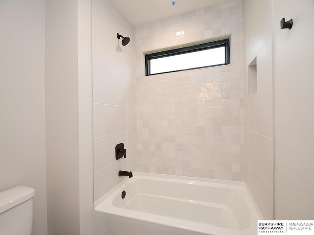 bathroom featuring tiled shower / bath and toilet