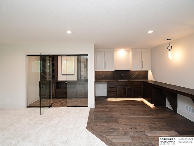 kitchen featuring white cabinetry, pendant lighting, dark carpet, tasteful backsplash, and sink