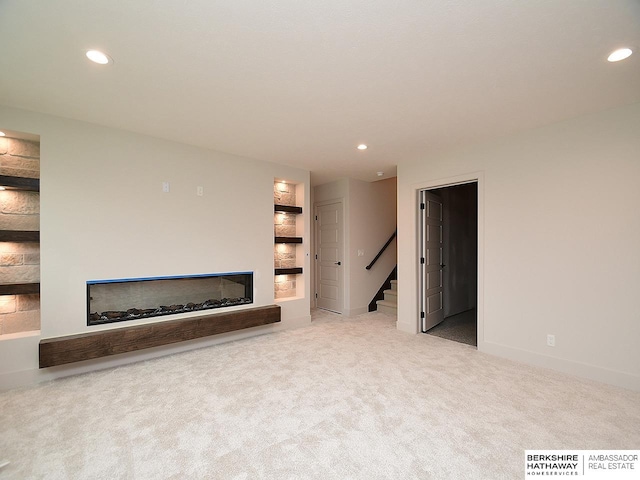 unfurnished living room featuring a fireplace and light colored carpet