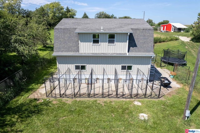 rear view of house with a patio, a trampoline, and a yard