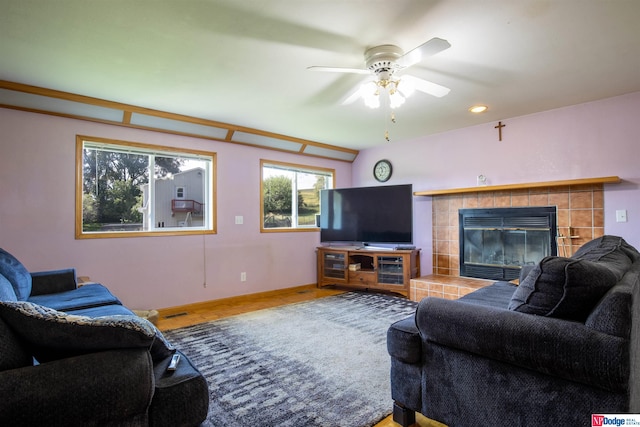 living room featuring a tile fireplace, hardwood / wood-style floors, and ceiling fan