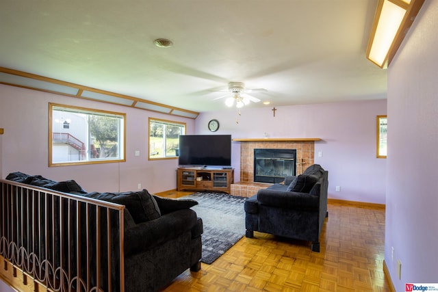 living room with a tile fireplace, light parquet flooring, and ceiling fan