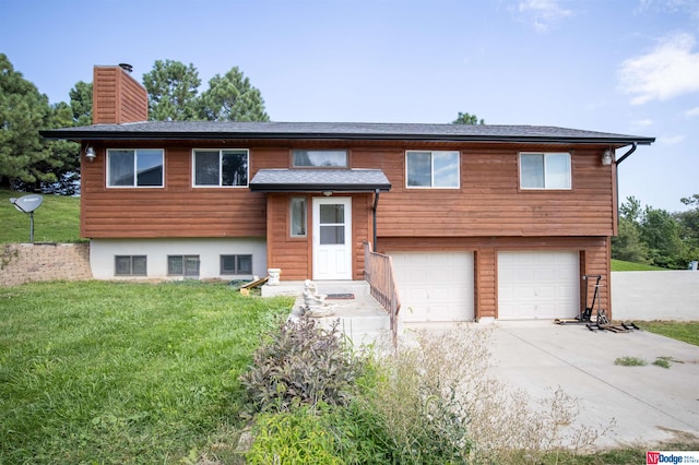 bi-level home featuring a garage and a front lawn